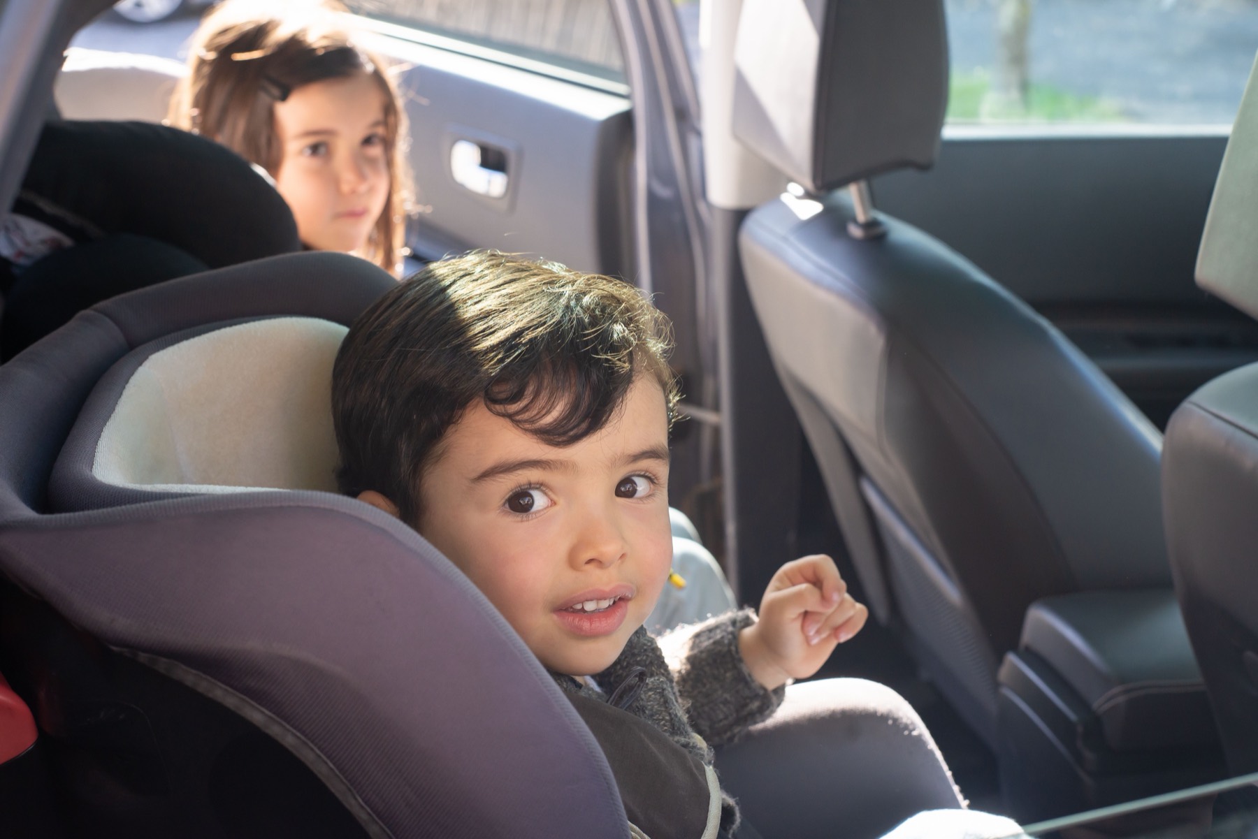 Smiling child in a child car seat, ready for a family trip