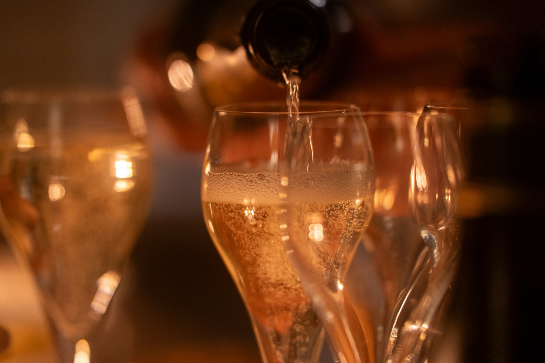 Champagne being poured into glasses in warm light