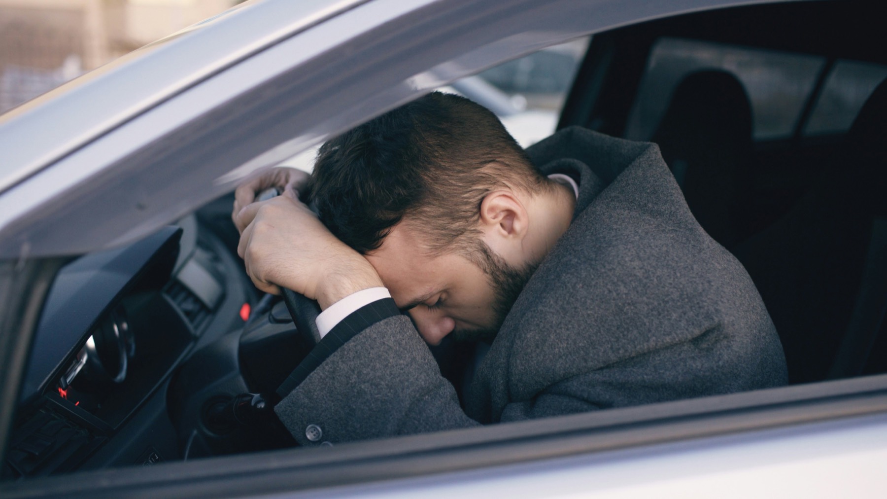 Tired businessman resting his head on the steering wheel