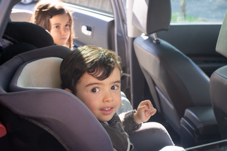 Smiling child in a child car seat, ready for a family trip